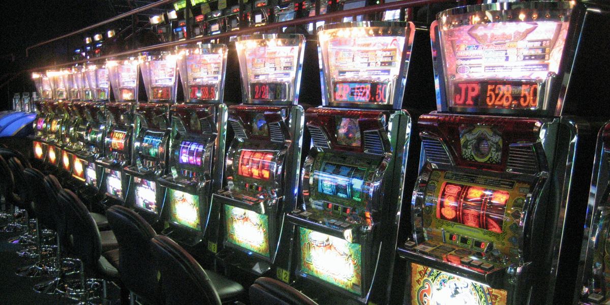 File di slot machine illuminate in una sala giochi