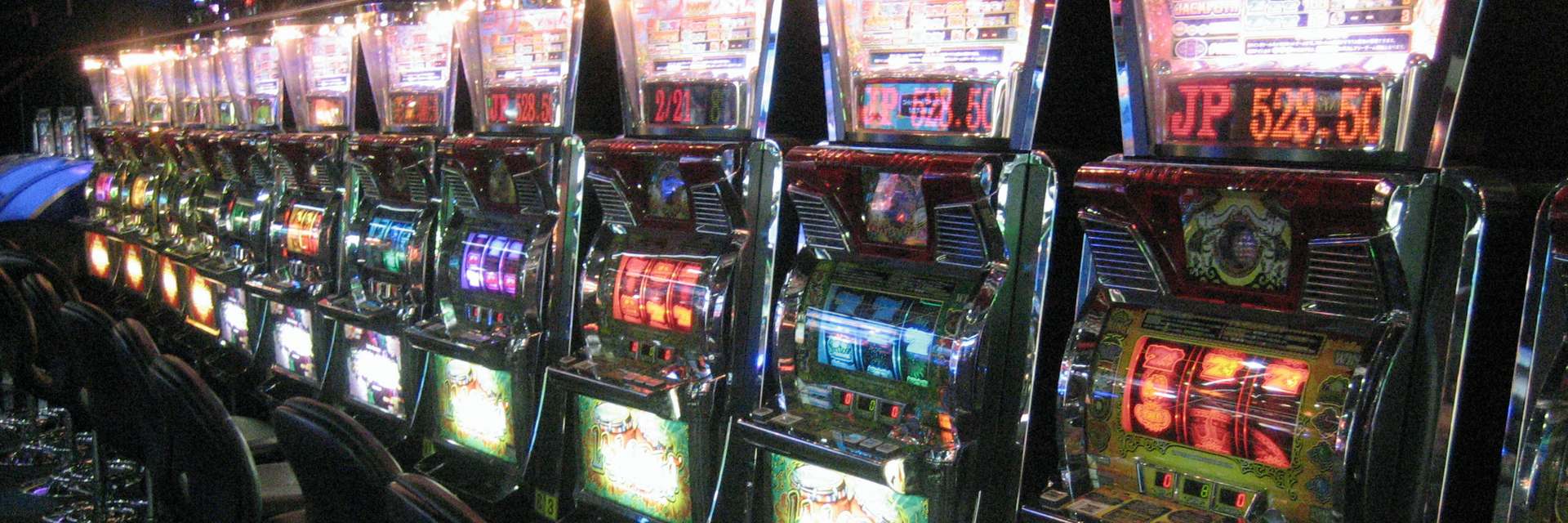 File di slot machine illuminate in una sala giochi